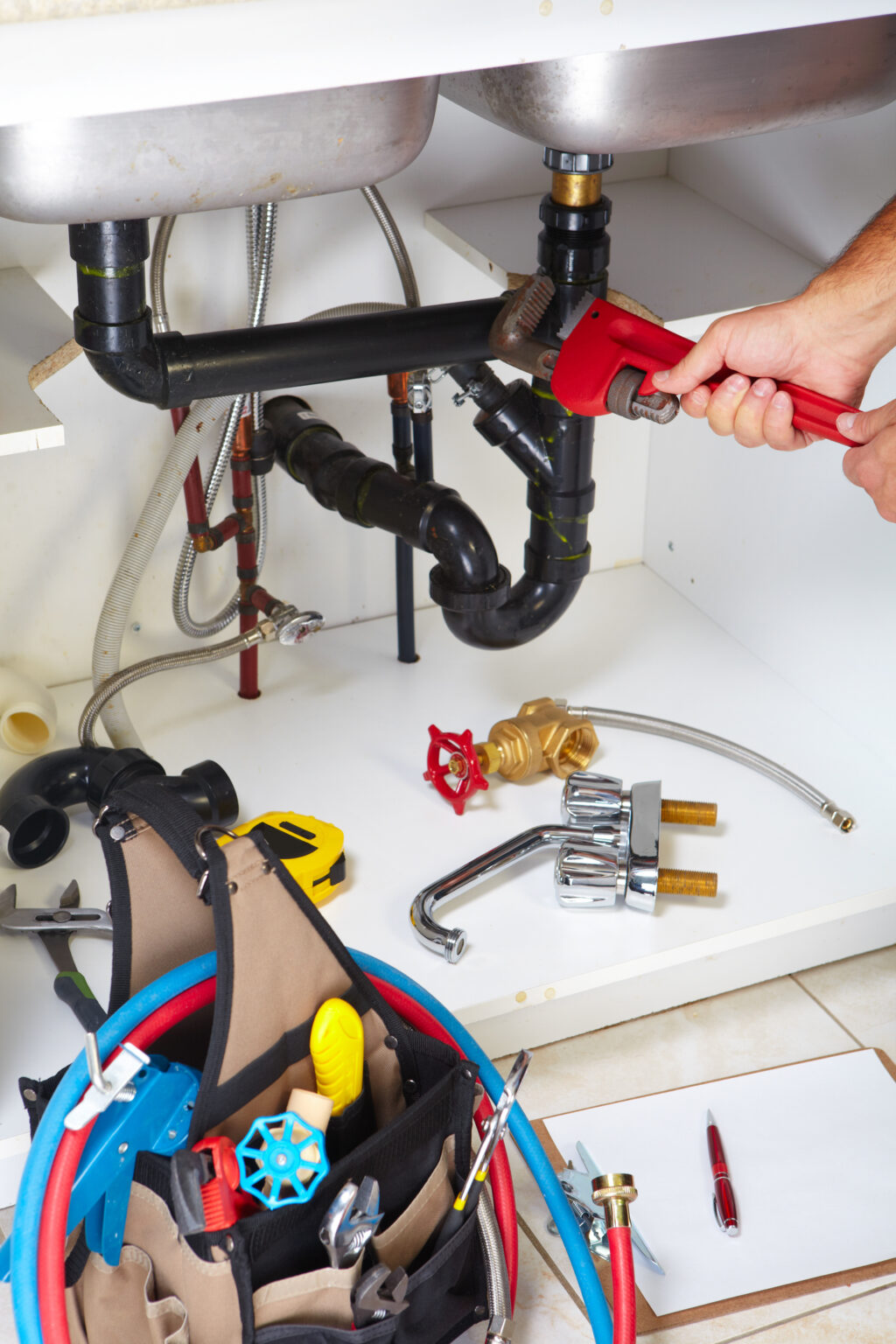 Plumber working under a kitchen sink to repair plumbing