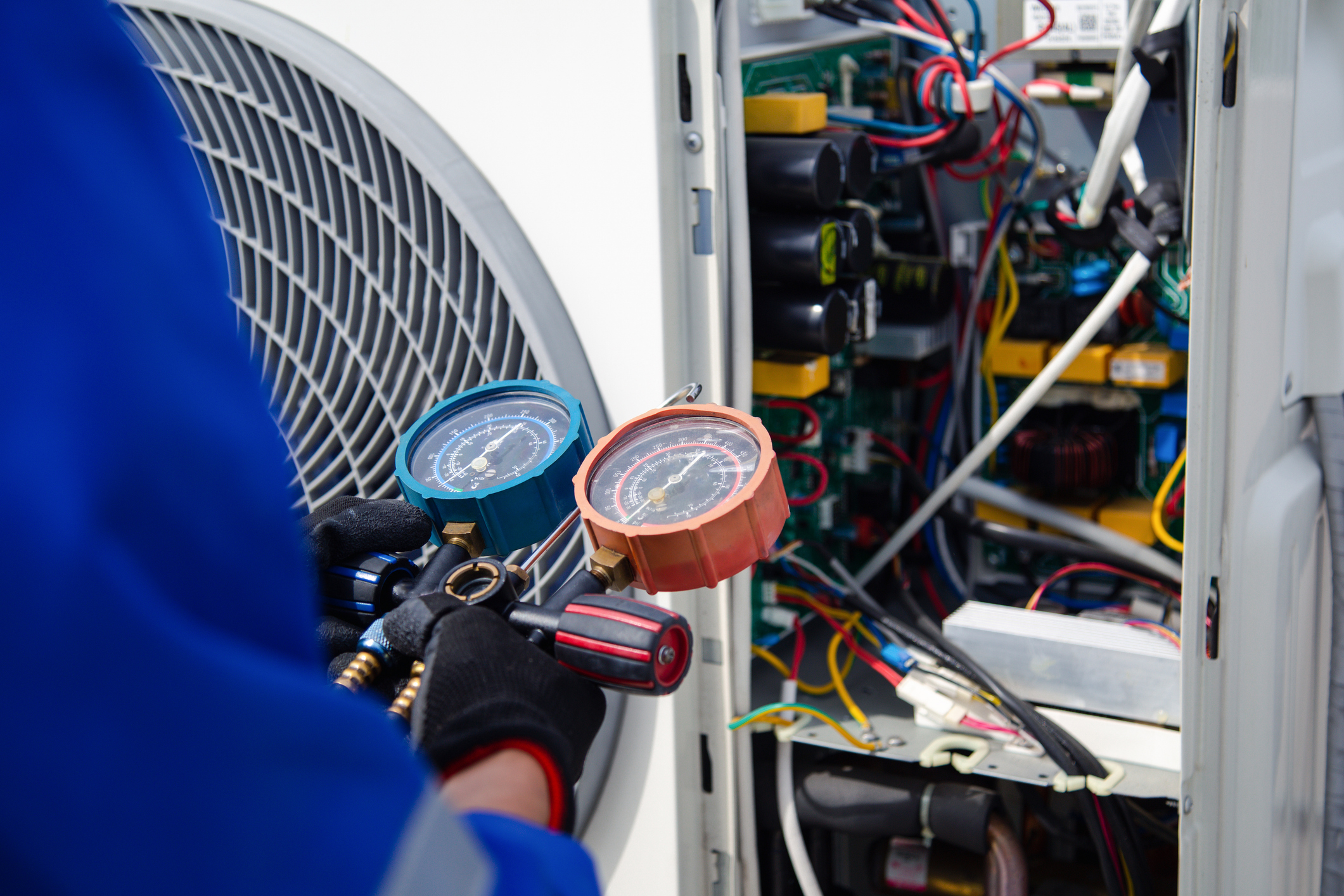 Air conditioner technician is using a gauge to measure the refrigerant pressure of an air compressor