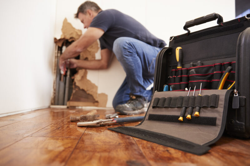 Middle aged man repairing burst pipe