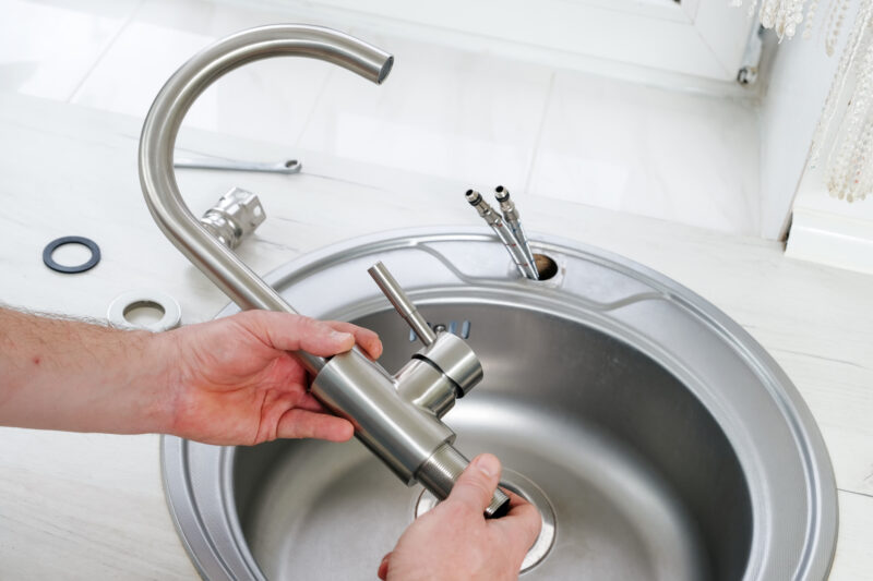  Close-up of plumber hands holding a new faucet for a kitchen sink