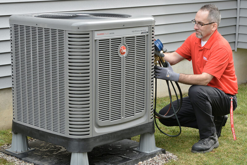 An employee checking out the external air conditioner and doing a checkup.