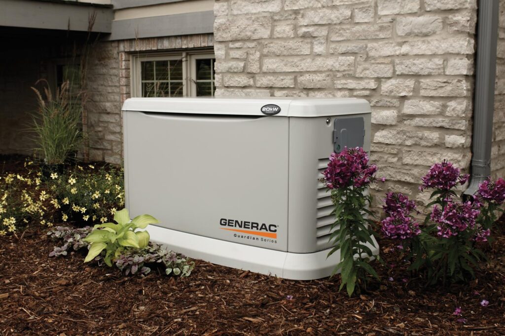 Generac generator against a stonewall surrounded by flowers